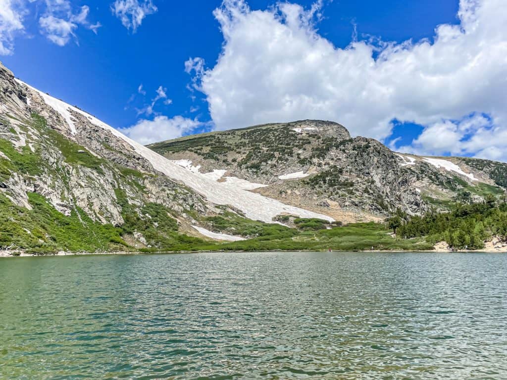 A white glacier is on a mountain near a lake.