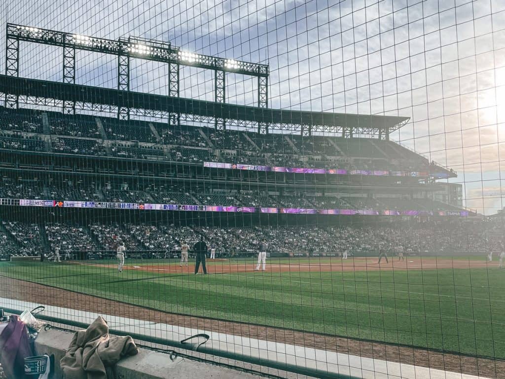 View of a baseball game from behind the net along the first base line. 