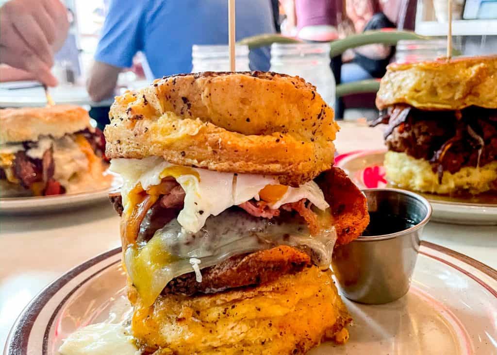 A massive biscuit sandwich with chicken, bacon, and eggs in it