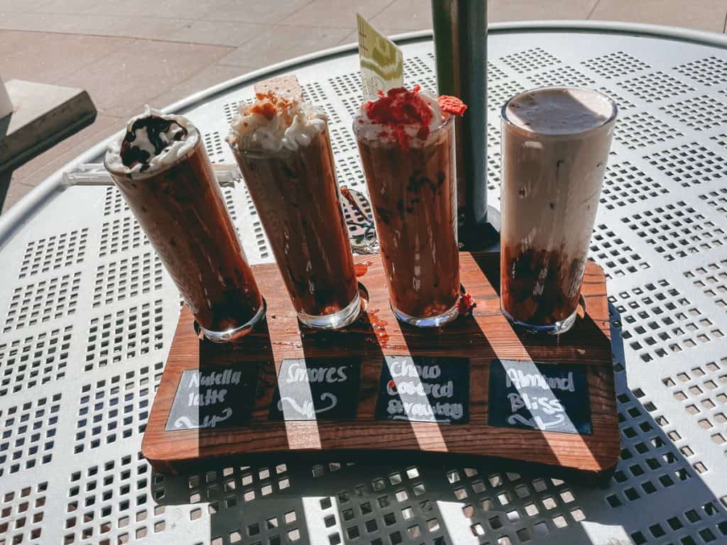 Four tall latte glasses on a wooden plank.