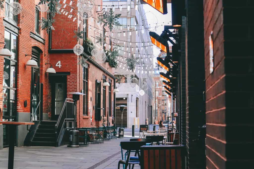 street alley with string lights and metal tables 