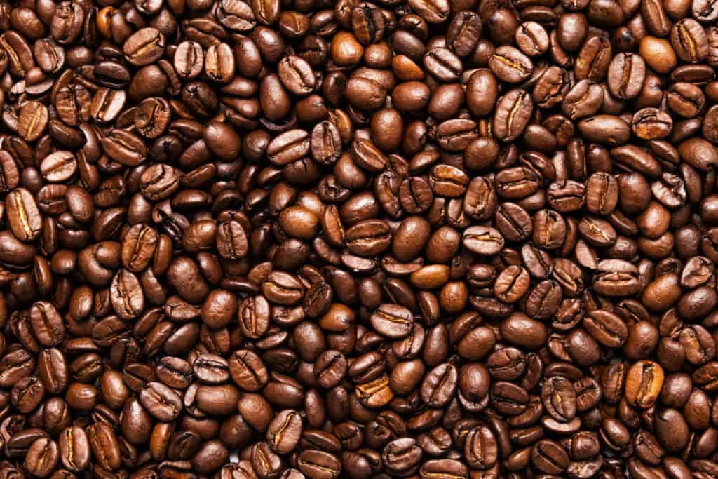 Full-frame texture of medium-roasted coffee beans, displaying a range of brown tones indicative of their roasting profile.