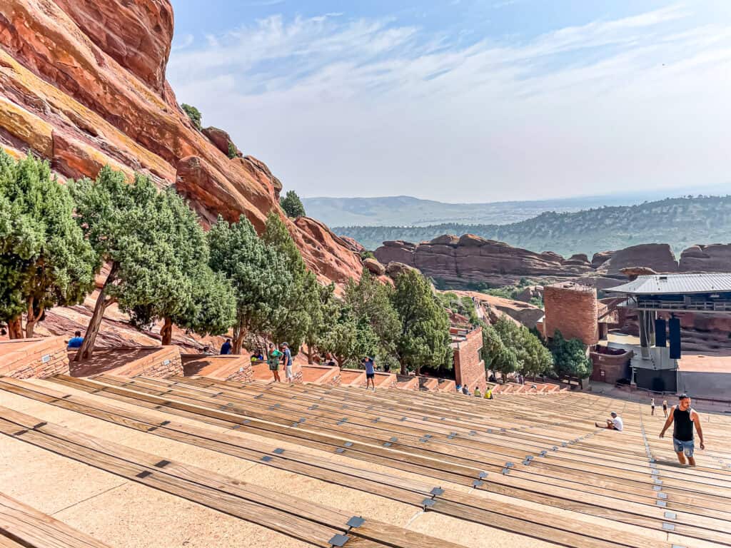 People walking around big red rocks at the Red Rocks Amphitheatre outside Denver.